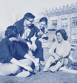 A vintage photo of four students sitting outside the Castle; a blue monotint has been applied to the photo.