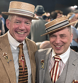 Two men in straw boaters and patterned suit and tie smile for the camera.
