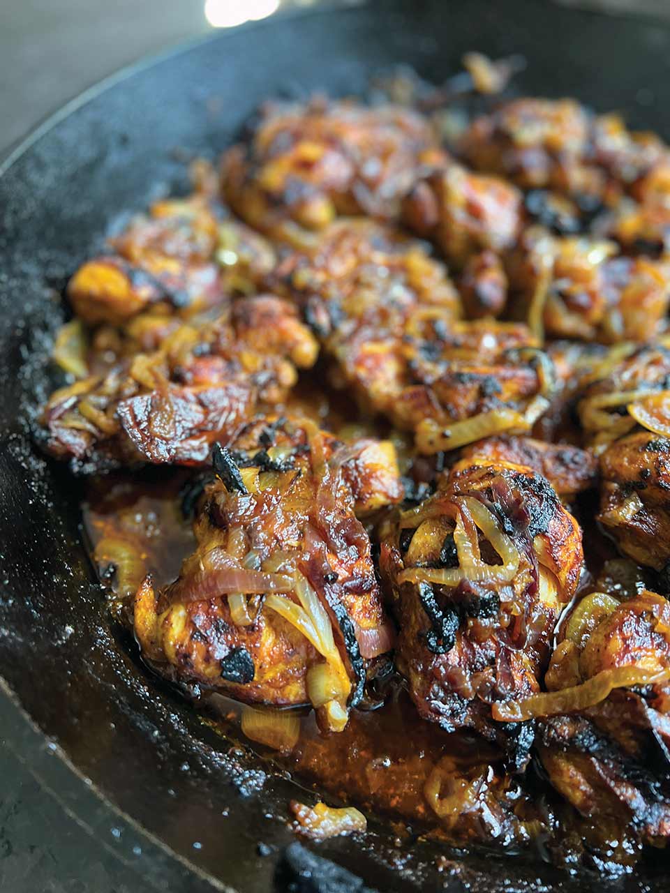 Browned and crispy chicken thighs and onions in a black cast-iron skillet