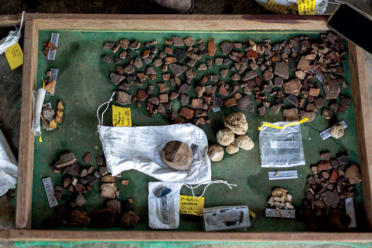 Stone artifacts in a collection tray, some with labels identifying them.