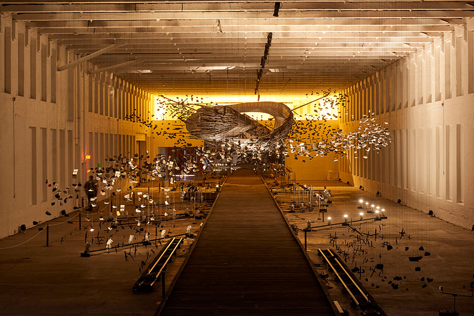 “In the Light of a Shadow” installation with various shapes and forms suspended from a ceiling by strings.