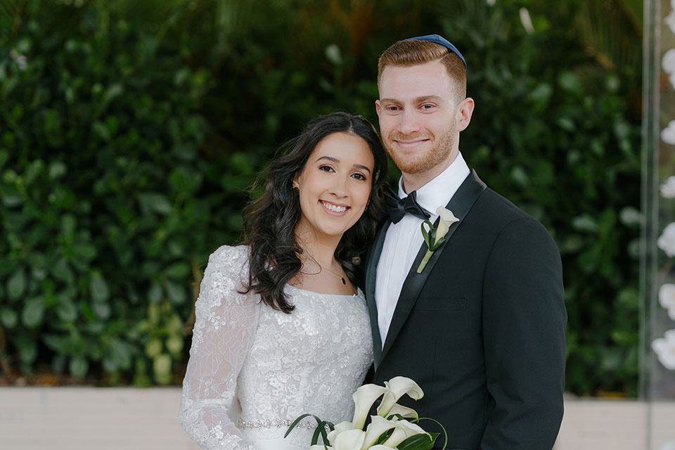 A bride and groom stand together and smile.