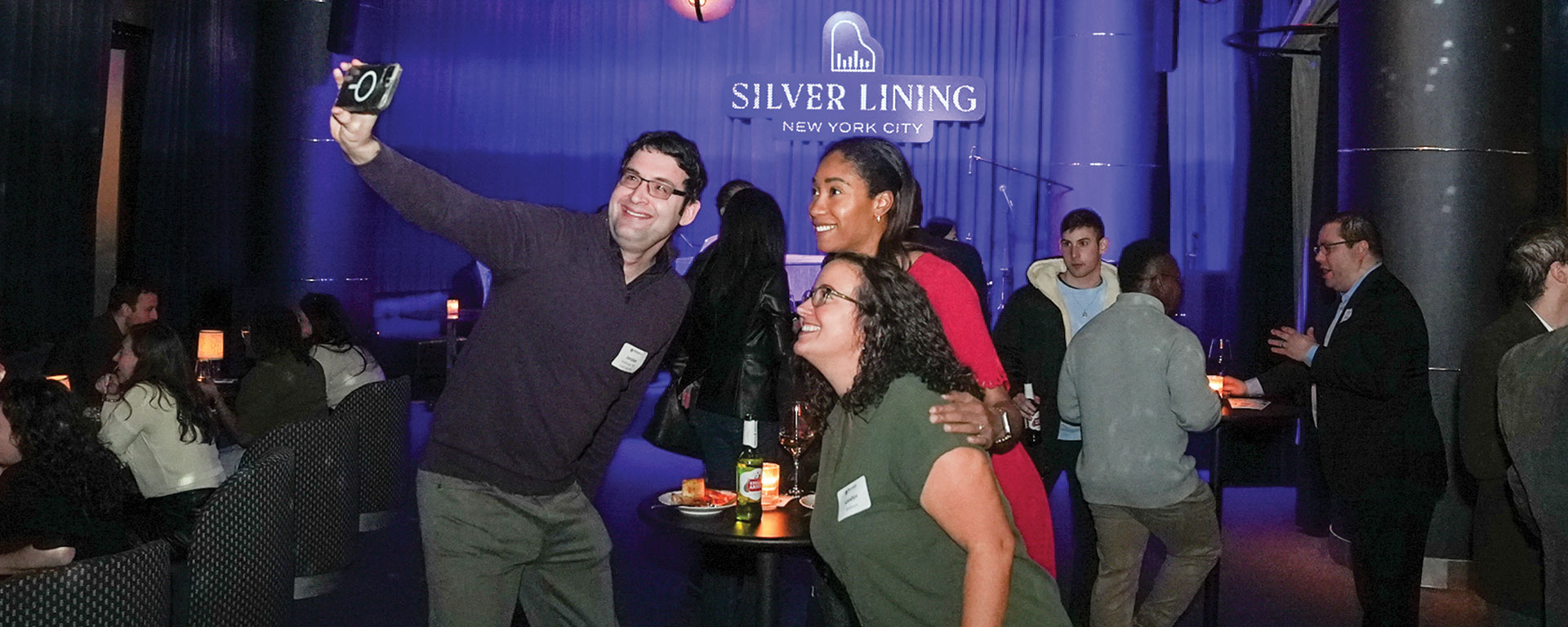 Three alumni take a selfie in a lounge at an alumni event.