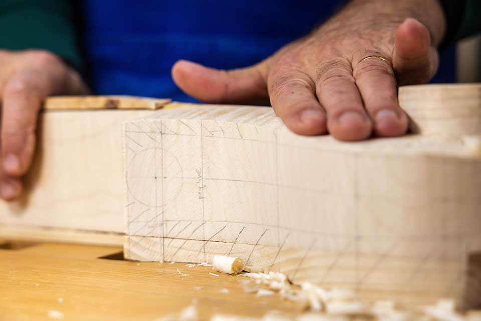 A close-up view of the beginning stages of a wooden cello's scroll.