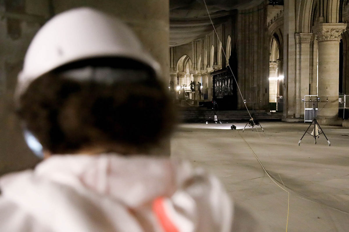 The robot is seen traveling through the cathedral, a person from Katz's team is seen in the foreground.