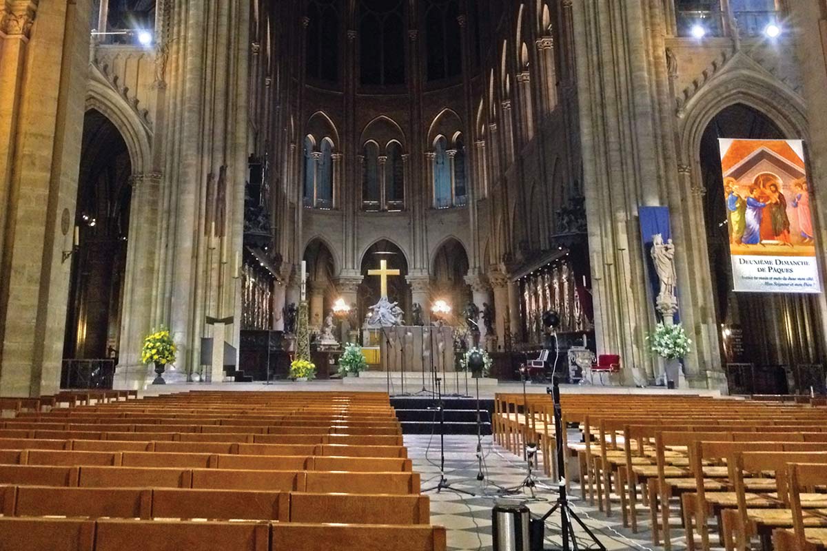 Interior of Notre-Dame Cathedral showing rows of wooden pews facing the altar.
