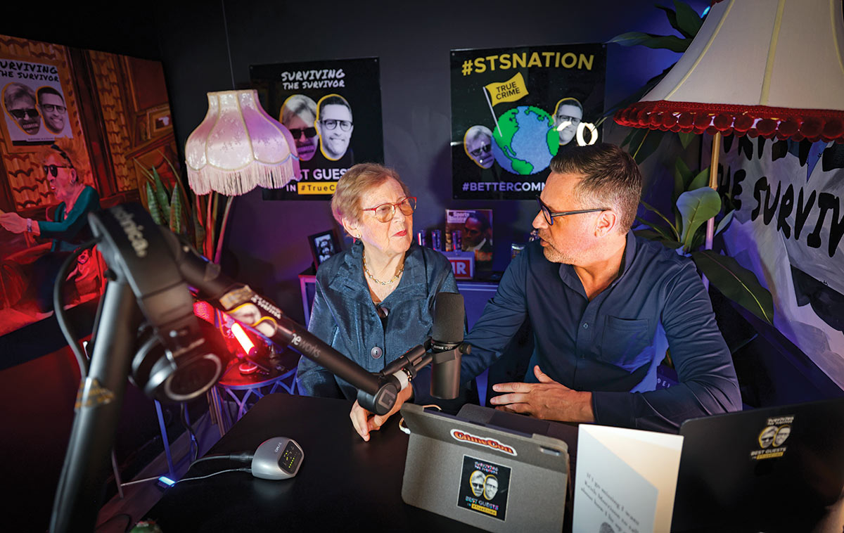 Two people speaking in a podcast recording room.