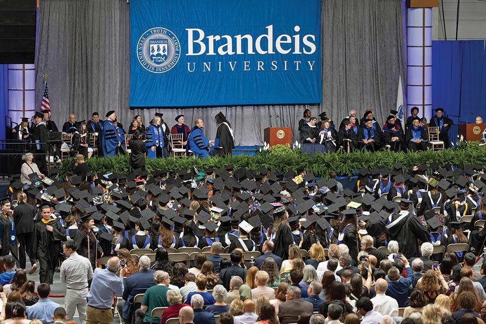 View inside Gosman during Commencement; graduates seated in the foreground, the stage in the background