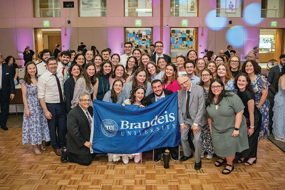 Samantha Brody and Eitan Marks hold up a Brandeis flag at their wedding.