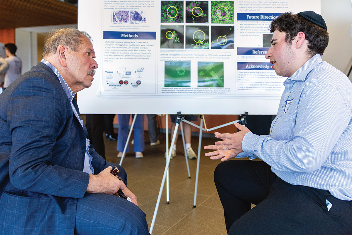Arthur Levine speaks with a student in front of a scientific poster