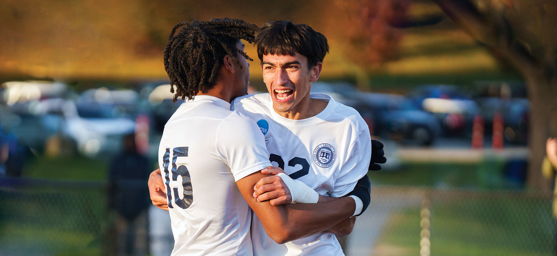 Two Brandeis soccer players hug each other and celebrate.