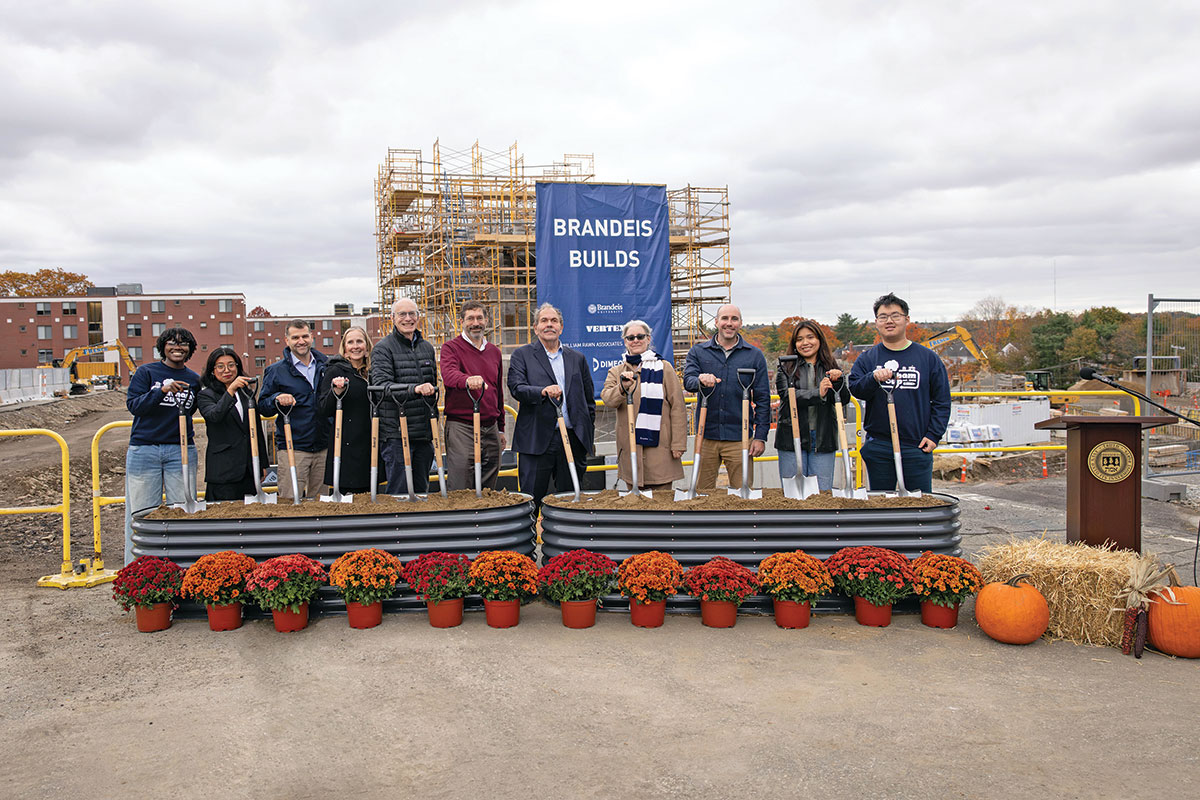Brandeis administrators and community members stand in front of the construction site of the new residence hall at the groundbreaking ceremony.