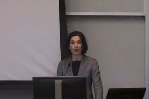A speaker stands at a podium addressing an audience.