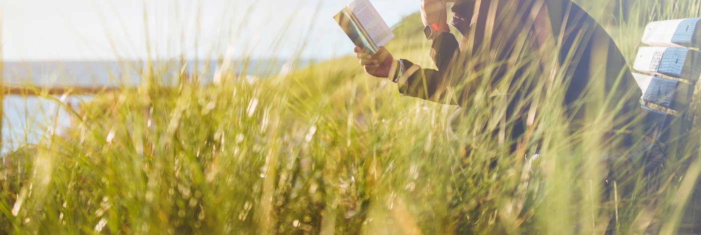 Reading outdoors on a bench near the beach