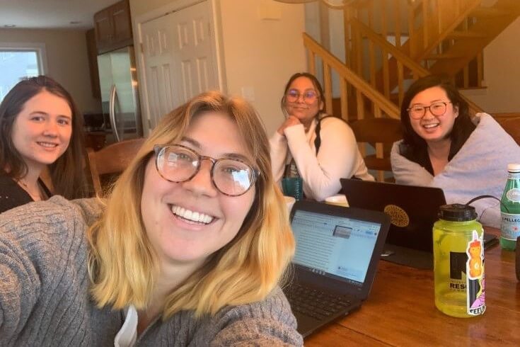 Four students at a table with laptops