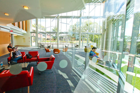 Students sitting in brightly colored furniture while working and lounging in the Mandel Center.