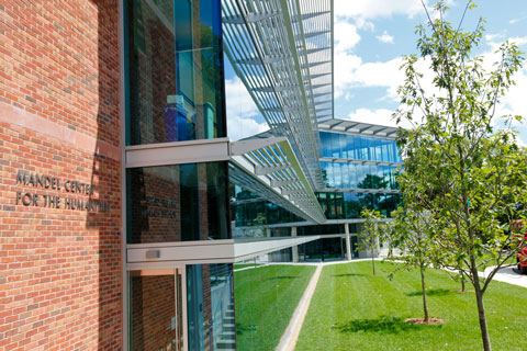 Exterior photo of the facade and green lawn in front of the Mandel Center for the Humanities on a sunny day.