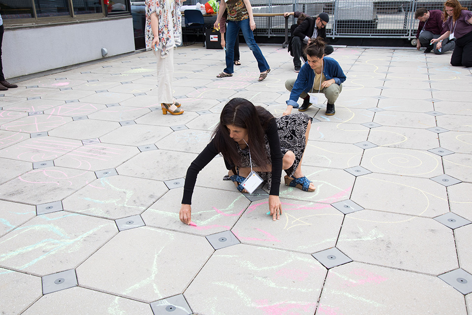 Adult participant drawing on ground with chalk.