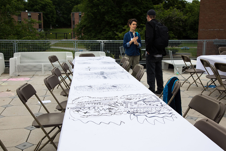 Long table with art and 2 people talking.