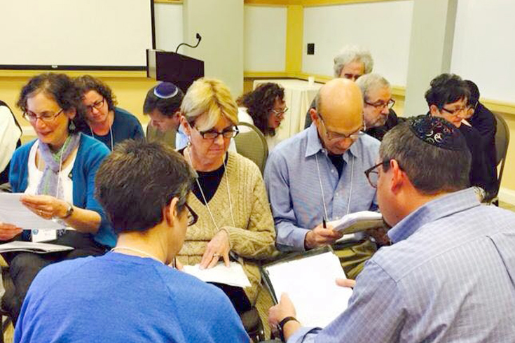 Group of people sitting in a circle, looking at papers