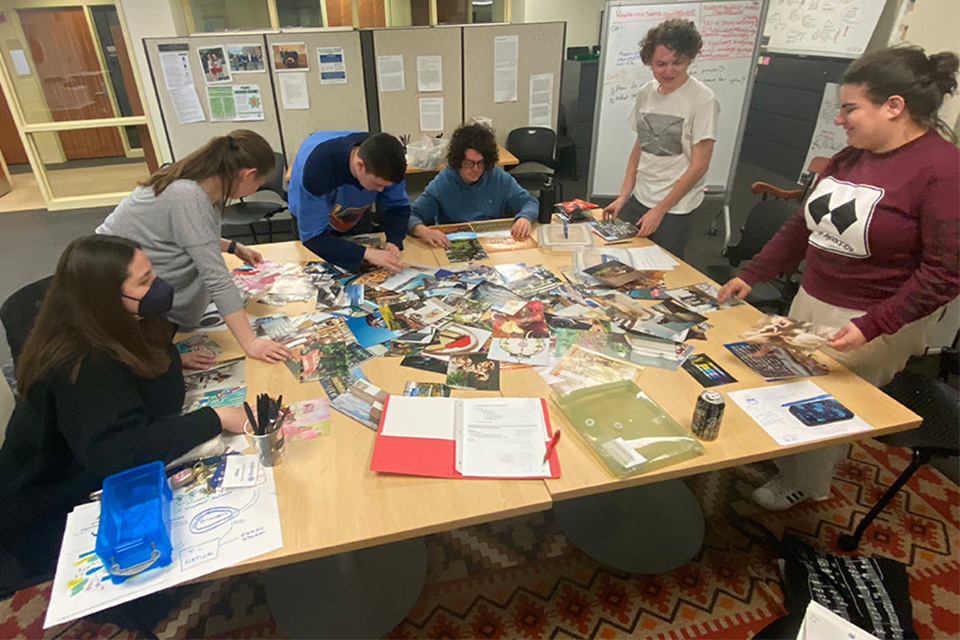 Group of students around a table covered with mixed media.
