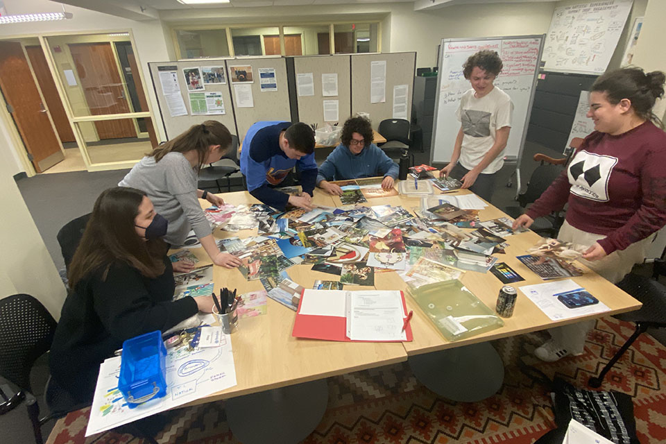 6 students working at a table covered with papers