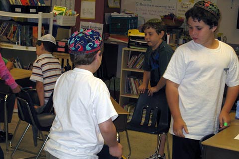 Students standing up beside their chairs in a classroom