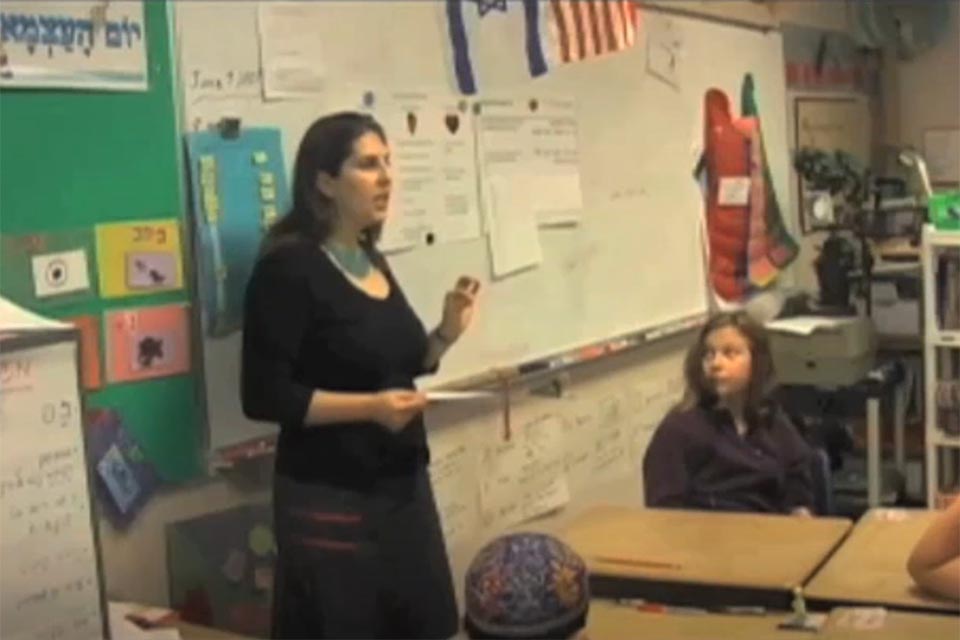Teacher talking to her class while standing in front of the board