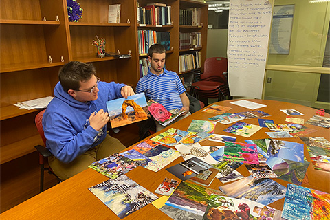 2 students at table full of magazine cut-outs