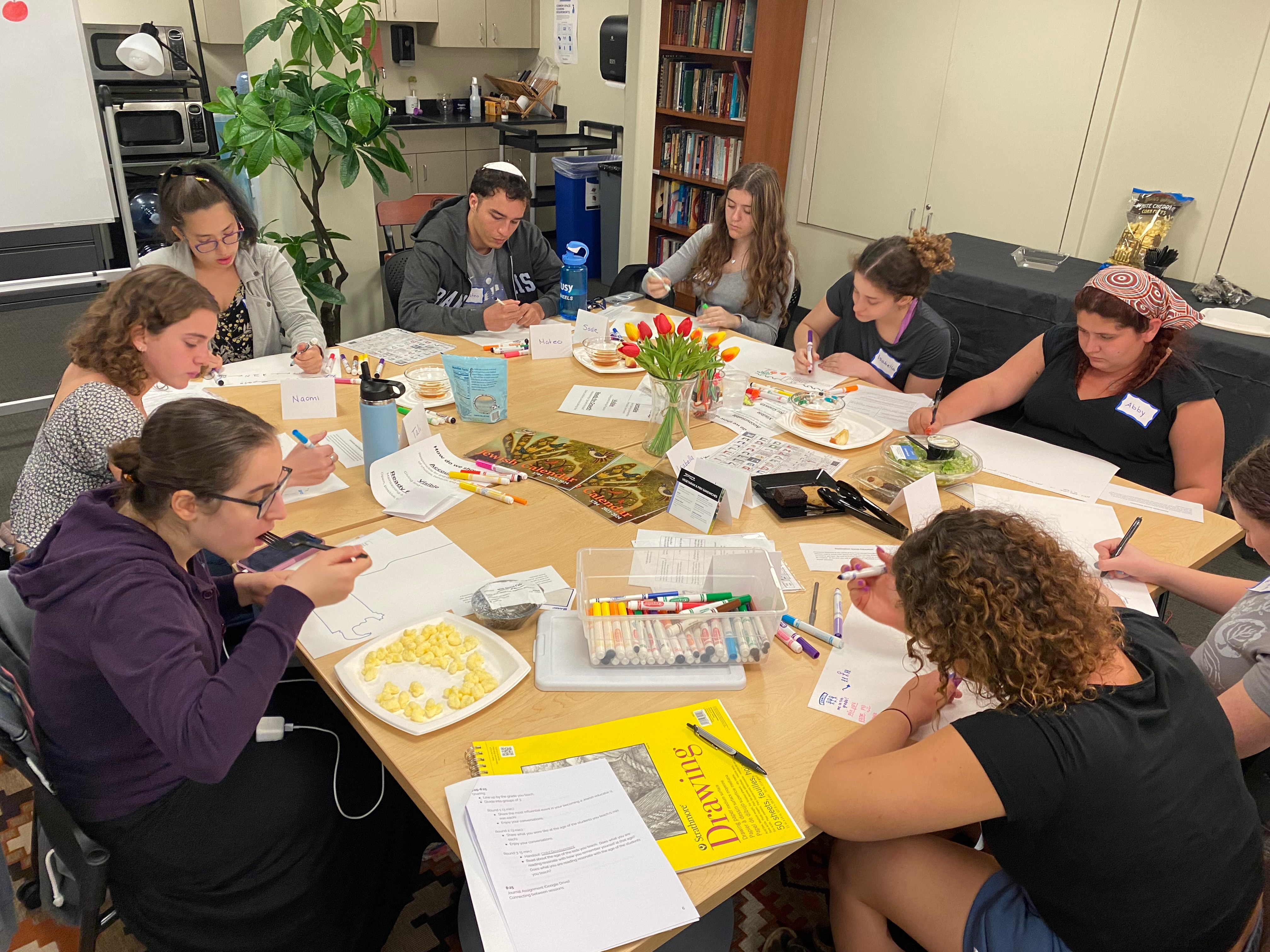 8 UTF students working around a big table with the artwork on it