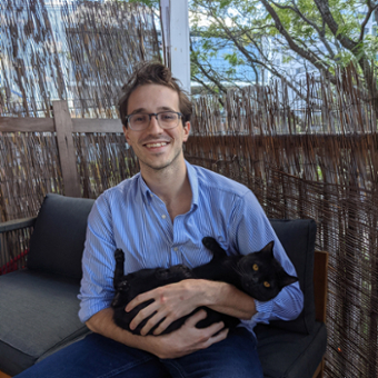 Thomas (Tom) Hansen smiling at the camera holding a black cat