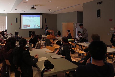 Participants watching a presentation.  Text on the slide reads: Bioinspired Soft Materials. Center Vision. “Create new materials with the functionalities found in living organisms, but constructed from a few simplified components."