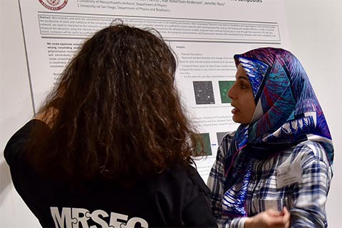 Two participants standing in front of a poster, engaged in discussion.