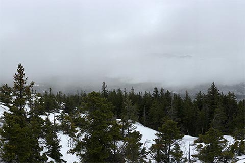 Panoramic vista of the White Mountains covered in snow with fog.