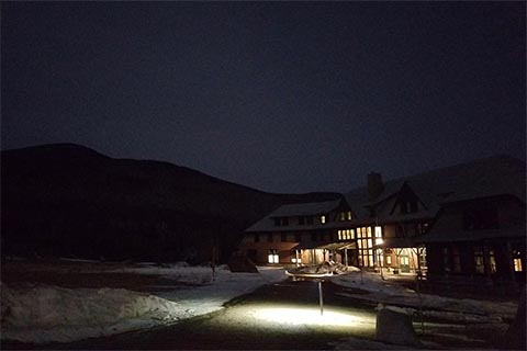 Nighttime view of the Highland Center against the backdrop of the mountains, with light emanating from the building.