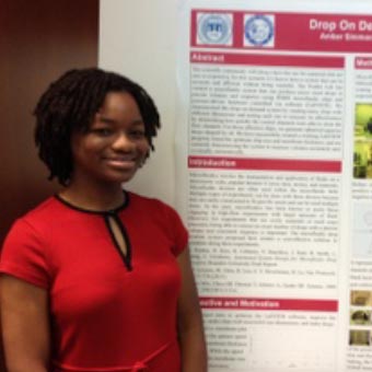 Amber Simmons standing in front of her poster at the Brandeis symposium.