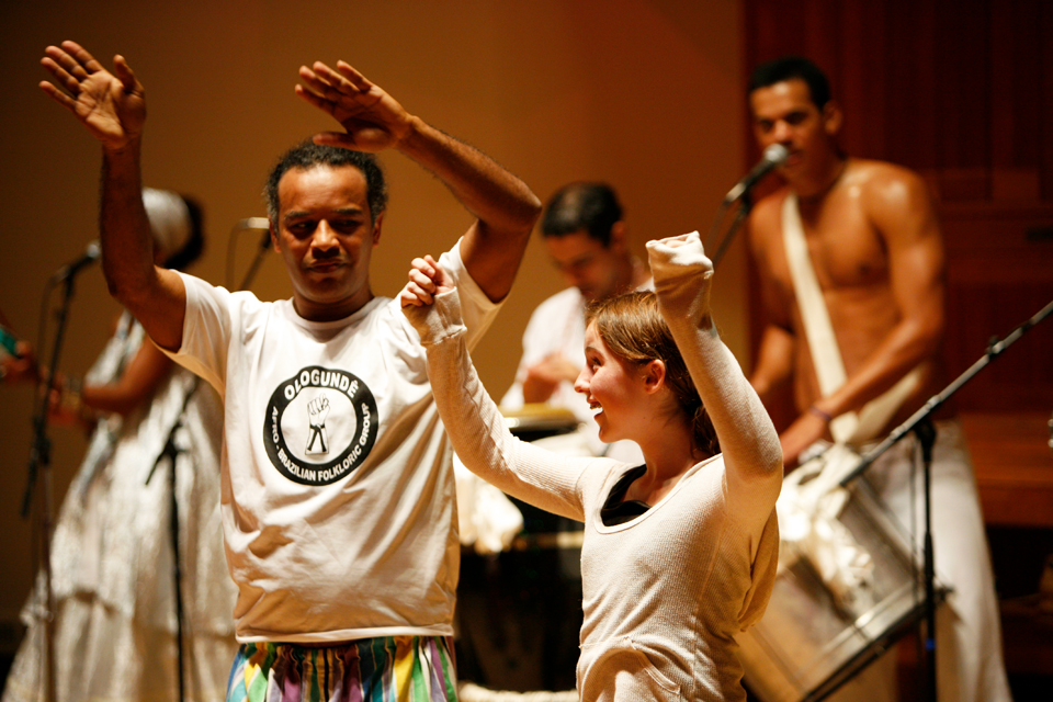 Members of guest ensemble Ologundê from Brazil teaching a Waltham middle school student.