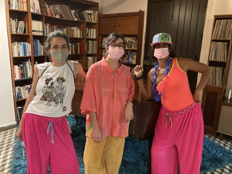 Three women pose in colorful costumes