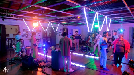 Musicians perform while surrounded by light bars