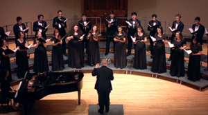 Chorus members, in formal dress, perform on risers in the Slosberg Music Center