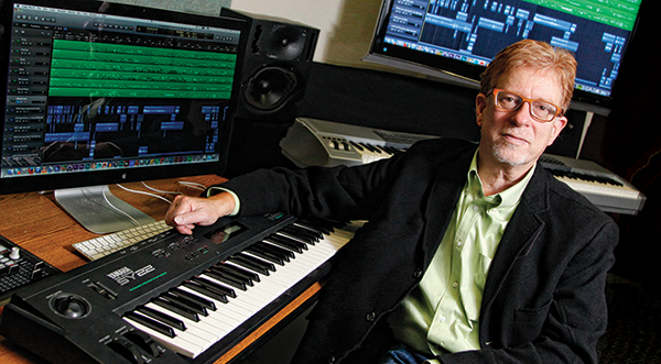 Eric Chasalow poses with multiple computers and keyboards