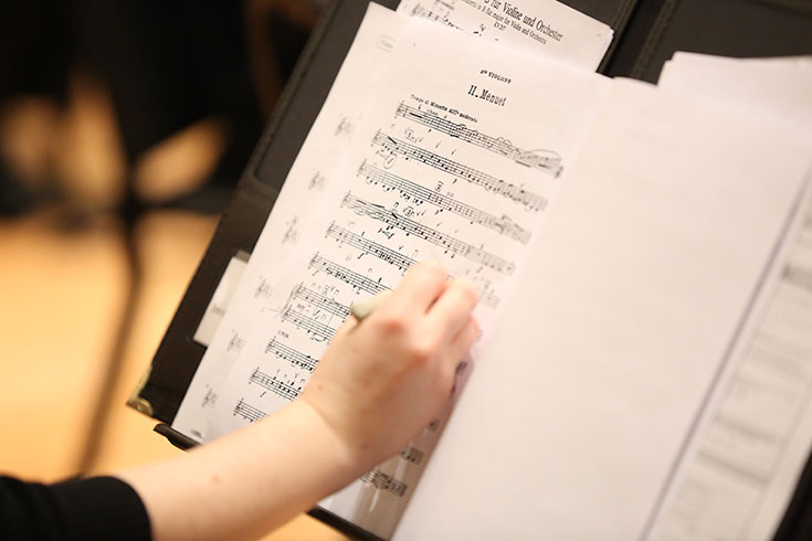 A hand writes on a sheet of music