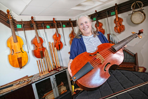 Sarah Mead poses with the string instruments in the Jencks Early Music Instrument Room