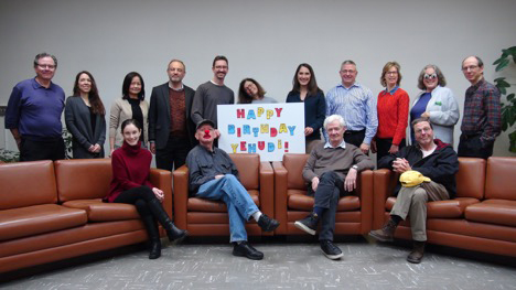 Members of the Music Department posing with a sign that reads, Happy Birthday Yehudi!