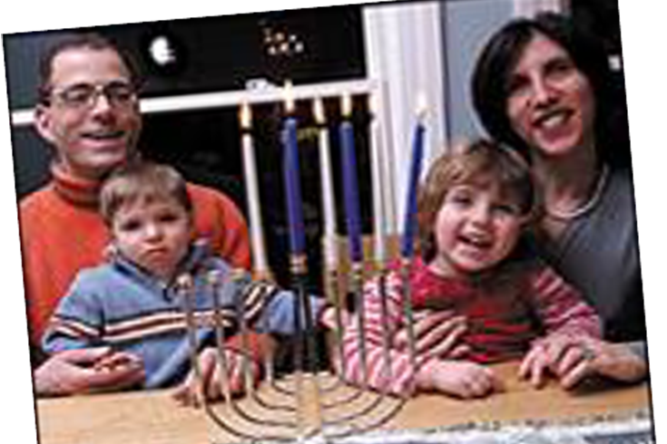 Family smiling and sitting at a table with a Menorah.