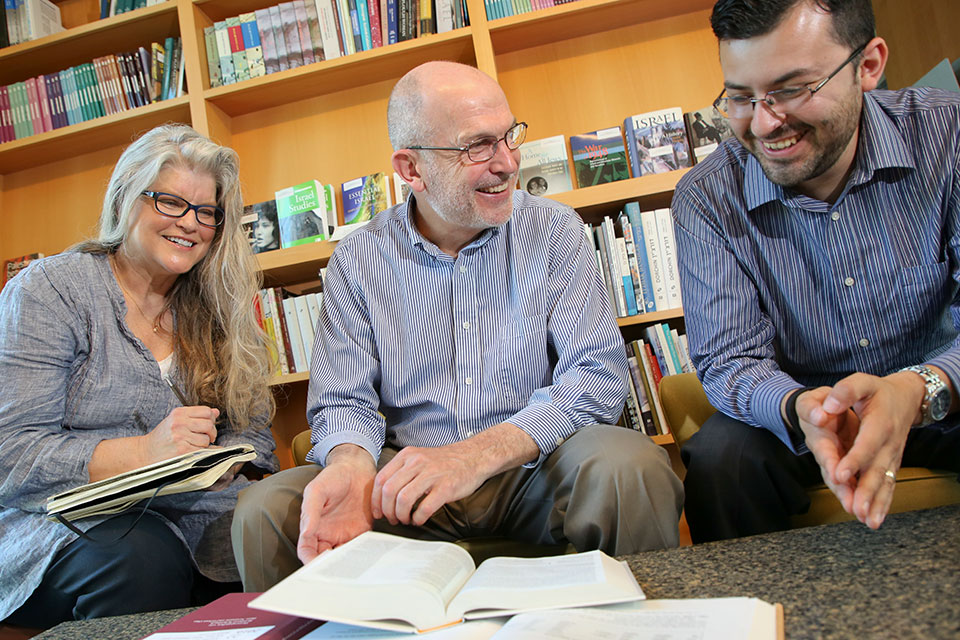 Two students sitting with a professor, laughing