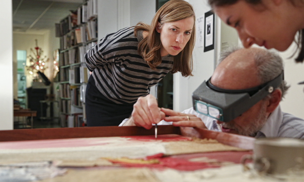 Kim Conaty, curator of the Rose Art Museum, looks on as a painting is cleaned.