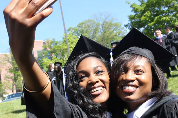 Two female graduates pose for a selfie.