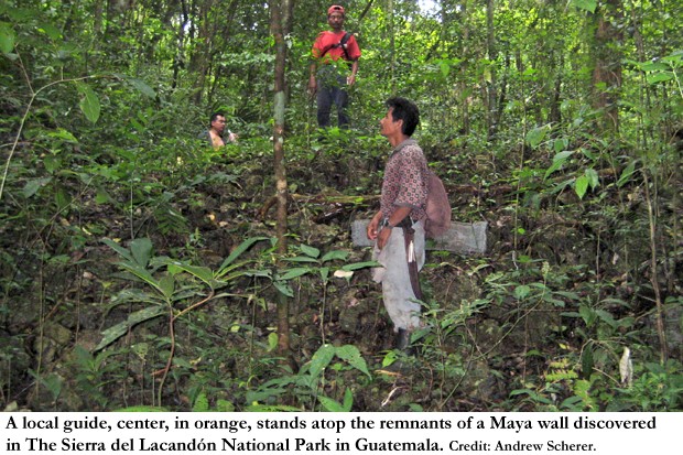 A local guide, center, in orange, stands atop the remnants of a Maya wall discovered in The Sierra del Lacandón National Park in Guatemala. 