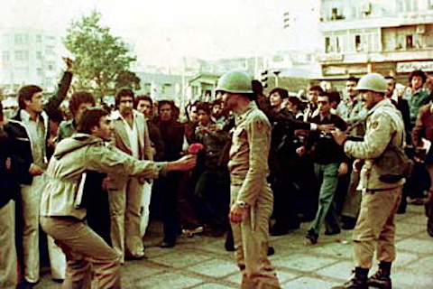 A man holds a flower out to a soldier.